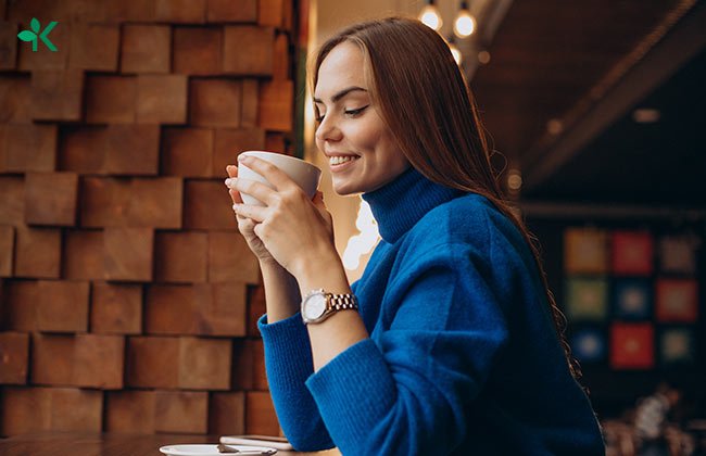 Mujer sonriendo con una taza de café de capomo en sus manos